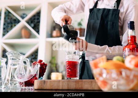 Der Barkeeper bereitet auf der Terrasse des Restaurants einen Beerencocktail zu. Stockfoto