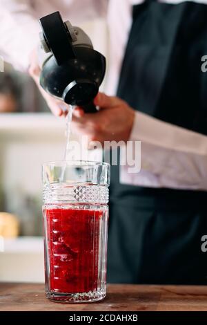 Der Barkeeper bereitet auf der Terrasse des Restaurants einen Beerencocktail zu. Stockfoto