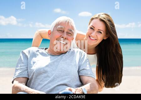 Glückliche Junge Frau Mit Ihrem Alten Älteren Vater Auf Rollstuhl Im Urlaub Stockfoto