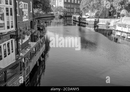 Ein Schwarz-Weiß-Foto von einem Blick auf den Wensum beim Schleifen auf der Fye Bridge, Magdalen Street in der Stadt Norwich. Auf der linken Seite befindet sich der beliebte Pub Ribs of Beef und sein kleiner Biergarten mit Blick auf den Fluss. Stockfoto