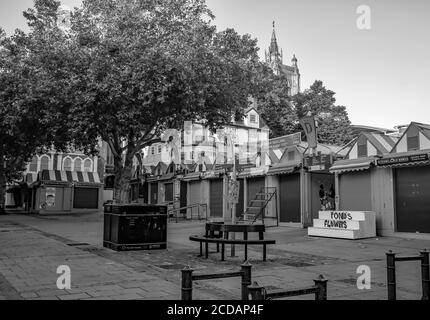 Ein Schwarz-Weiß-Foto von der Front des Norwich Outdoor-Marktes, Gewinner des 'Best Outdoor Market' im Jahr 2019, an einem hellen und sonnigen Tag. Im Hintergrund befindet sich der Turm der Kirche St. Peter Mancroft. Stockfoto