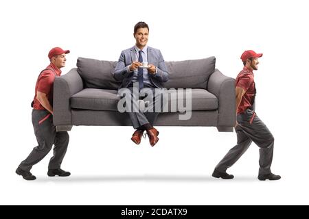 Mann in eleganten Kleidern sitzt auf einem Sofa mit einem tasse Kaffee, während zwei Mover das Sofa tragen In einem Transporter isoliert auf weißem Hintergrund Stockfoto