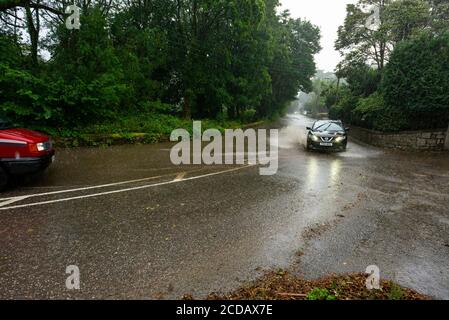 Par, Cornwall, 27/08/2020. Autos sprühen riesige Sprays auf, während sie nach heftigen Regenfällen durch die überfluteten Straßen in Cornwall kämpfen. Stockfoto