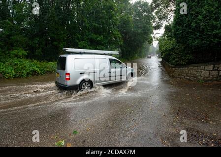 Par, Cornwall, 27/08/2020. Autos sprühen riesige Sprays auf, während sie nach heftigen Regenfällen durch die überfluteten Straßen in Cornwall kämpfen. Stockfoto