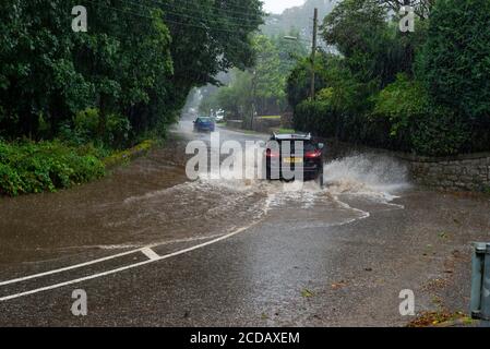 Par, Cornwall, 27/08/2020. Autos sprühen riesige Sprays auf, während sie nach heftigen Regenfällen durch die überfluteten Straßen in Cornwall kämpfen. Stockfoto