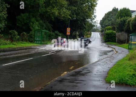 Par, Cornwall, 27/08/2020. Autos sprühen riesige Sprays auf, während sie nach heftigen Regenfällen durch die überfluteten Straßen in Cornwall kämpfen. Stockfoto