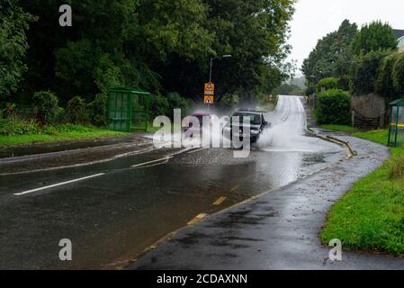 Par, Cornwall, 27/08/2020. Autos sprühen riesige Sprays auf, während sie nach heftigen Regenfällen durch die überfluteten Straßen in Cornwall kämpfen. Stockfoto