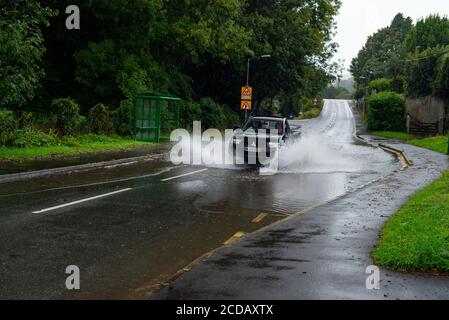 Par, Cornwall, 27/08/2020. Autos sprühen riesige Sprays auf, während sie nach heftigen Regenfällen durch die überfluteten Straßen in Cornwall kämpfen. Stockfoto