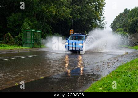 Par, Cornwall, 27/08/2020. Autos sprühen riesige Sprays auf, während sie nach heftigen Regenfällen durch die überfluteten Straßen in Cornwall kämpfen. Stockfoto