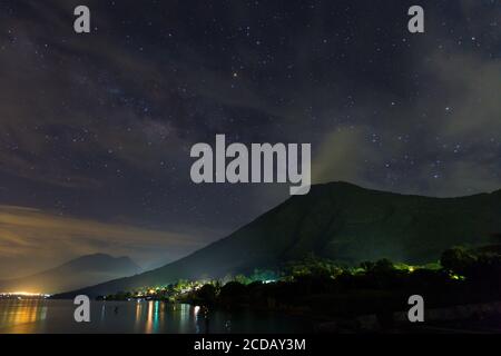 Sterne und Wolken über dem San Pedro Vulkan, einem schlafenden Vulkan am Atitlan See in Guatemala. Das Licht auf den Wolken ist von der Stadt Lichter um t Stockfoto