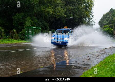 Par, Cornwall, 27/08/2020. Autos sprühen riesige Sprays auf, während sie nach heftigen Regenfällen durch die überfluteten Straßen in Cornwall kämpfen. Stockfoto