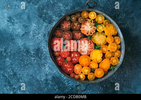 Tomaten in Scheiben verschiedener Farben werden als Farbverlauf auf einem dunklen Hintergrund dargestellt. Stockfoto