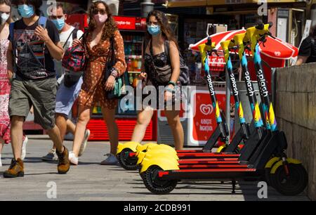 Bukarest, Rumänien - 23. Juli 2020: Die Menschen gehen neben vielen Splash Elektro-Scooter (selektiver Fokus) auf einem Bürgersteig in Bukarest geparkt. Dieses Bild Stockfoto