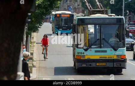Bukarest, Rumänien - 30. Juni 2020: Eine Frau auf Radfahrten neben einem Obus der Verkehrsgesellschaft Bukarest im Verkehr auf dem Regina Elisabeta Boulevard Stockfoto