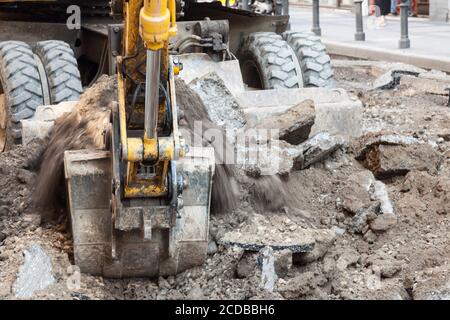 Konzentrieren Sie sich auf Kies und Schmutz aus dem Schauraum eines mechanischen Baggers Bagger arbeiten auf einer Baustelle eines Straße Sanierung städtischen Programms. Stockfoto