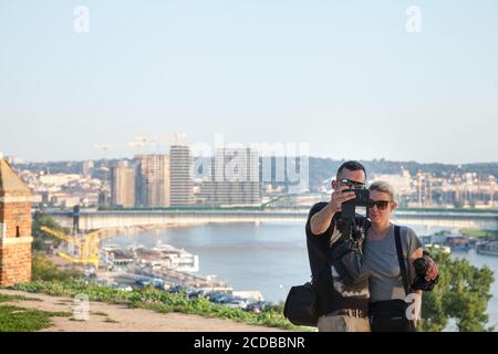 BELGRAD, SERBIEN - 11. JULI 2018: Ein paar Touristen machen ein Selfie mit einem Smartphone vor einem Panorama von Belgrad mit dem fluss sava aus t Stockfoto