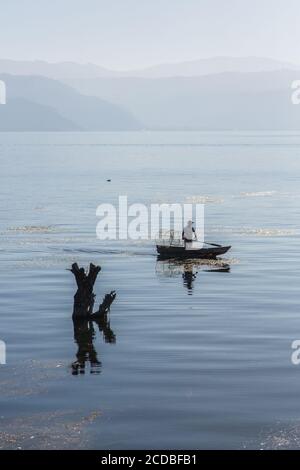 Ein Maya-Fischer mit seiner Drahtfalle in seinem Cayuco oder Kanu auf dem Atitlan-See bei San Pedro la Laguna, Guatemala. Steigende See Gewässer seit 2009 haben Stockfoto