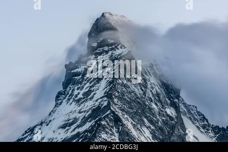 Langaufnahme des schneebedeckten Matterhorn-Berggipfels mit Wolke Im Sommer bei Dämmerung vor dem Berg vorbeifahren Aufgenommen aus Zermatt in den Schweizer Alpen Stockfoto