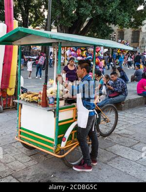 Ein Verkäufer, der Eloten und Ezitate auf dem Zocalo im historischen Zentrum von Oaxaca, Mexiko verkauft. Elotes sind Mais auf dem Kob, die zuerst gekocht werden, dann Stockfoto