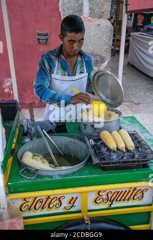 Ein Verkäufer, der Eloten und Ezitate auf der Straße im historischen Zentrum von Oaxaca, Mexiko verkauft. Elotes sind Mais auf dem Kob, die zuerst gekocht werden, dann Stockfoto