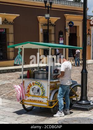 Ein Verkäufer, der Eloten und Ezitate auf der Straße im historischen Zentrum von Oaxaca, Mexiko verkauft. Elotes sind Mais auf dem Kob, die zuerst gekocht werden, dann Stockfoto