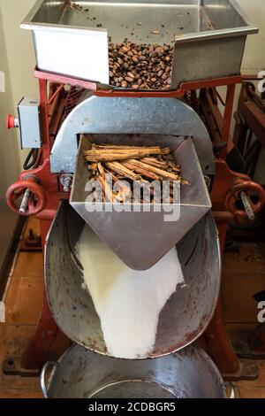 Geröstete Kakaobohnen und Zimtstangen in einer Maschine für Mahlen und Mischen mit Zucker zu Kakaopulver Im Mayordomo House of Chocolate Stockfoto