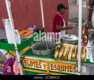 Ein Verkäufer, der Eloten und Ezitate auf der Straße im historischen Zentrum von Oaxaca, Mexiko verkauft. Elotes sind Mais auf dem Kob, die zuerst gekocht werden, dann Stockfoto