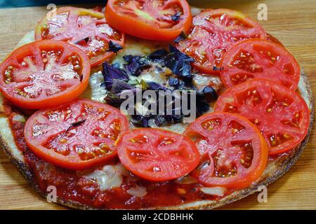 Hausgemachte Pizza mit frisch geschnittenen Tomaten und lila Basilikum auf Eine Blumenkohlkruste Stockfoto