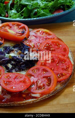 Hausgemachte Pizza mit frisch geschnittenen Tomaten und lila Basilikum auf Eine Blumenkohlkruste Stockfoto
