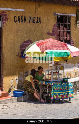 Tzutujil Maya Frauen in traditioneller Kleidung verkaufen Obst an einem Stand auf einer Straße in San Juan la Laguna, Guatemala. Stockfoto