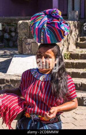 Eine Cakchiquel Maya Frau in traditioneller Kleidung trägt ihre Waren auf dem Markt in San Marcos la Laguna, Guatemala zu verkaufen. Stockfoto