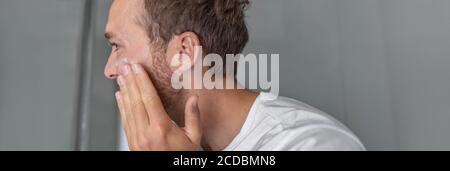 Mann Schönheit Anwendung Gesichtscreme für Gesichts Pickel Behandlung in Home Bad Blick auf Spiegel Panorama-Banner. Männer Hautpflege Hautpflege Lebensstil Stockfoto