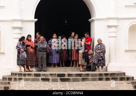 Mehrere Personen auf den Stufen der Kirche in San Pedro la Laguna, Guatemala. Die Frauen sind in traditioneller Kleidung, während die Männer moderne Kleidung tragen. Stockfoto