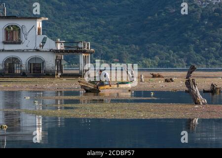 Ein Maya-Fischer in seinem Cayuco prüft seine Krabbenfalle vor einem überfluteten Gebäude in San Pedro la Laguna. Seit 2009 hat der Atitlan See in Guatemala Stockfoto