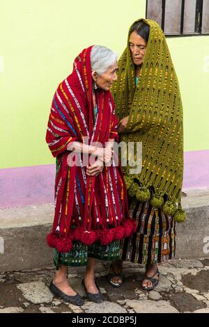 Zwei alte Frauen, Mutter und Tochter in traditioneller Tracht mit ihre Kopftücher über ihre Köpfe hinweg sehen eine nähert sich katholische religiöse Prozession in Stockfoto