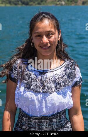 Eine attraktive junge Tzutujil Maya Frau in einer traditionellen bestickten Huipil Bluse posiert für ein Porträt in Santiago Atitlan, Guatemala. Stockfoto