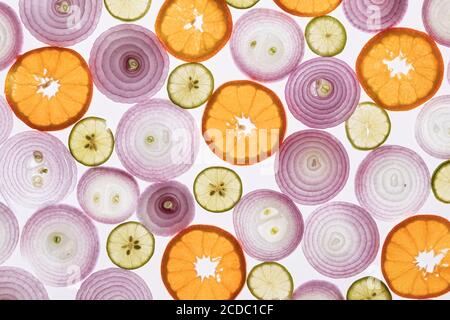 Zwiebeln, Zitronen und Orangen Hintergrund. Zwiebel, Zitronen und Orangen in Scheiben geschnitten. Hintergrundbeleuchtete Fotografie. Licht durchdringt die Elemente. Kombination von Farben. Stockfoto