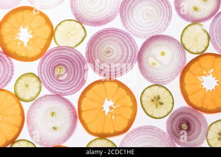 Zwiebeln, Zitronen und Orangen Hintergrund. Zwiebel, Zitronen und Orangen in Scheiben geschnitten. Hintergrundbeleuchtete Fotografie. Licht durchdringt die Elemente. Kombination von Farben. Stockfoto