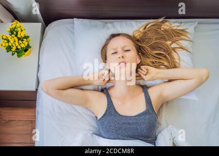 Verärgert junge Frau im Bett liegend am Morgen fühlt Schmerzen im Nacken nach dem Nachtschlaf, erwachen mit schmerzhaften plötzlichen Schmerzen oder Steifheit, falsche Haltung Stockfoto