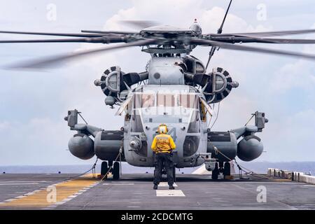 200826-N-RU810-1144 PHILIPPINISCHES MEER (AUG 26, 2020) Aviation Boatswain's Mate (Handling) 3rd Class Breanna Delafuente, aus Long Beach, Mississippi, dem forward-deployed amphibious Assault ship USS America (LHA 6) zugeordnet, bereitet sich auf den Start eines CH-53 Super Hengst Hubschrauber der 31st Marine Expeditionary Unit (MEU), Marine Medium Tiltrotor Squadron (VMM) 262 vom Deck des Schiffes aus. America, Flaggschiff der America Expeditionary Strike Group, 31. Marine Expeditionary Unit Team, ist im 7. US-Flottenbereich tätig, um die Interoperabilität mit Alliierten und Partn zu verbessern Stockfoto