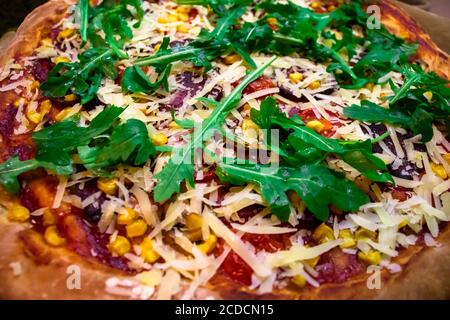 Pizza mit frischen grünen Rucola, Parmesan-Käse und Kirschtomaten Essen Hintergrund. Frisch gebackene hausgemachte Pizza Stockfoto