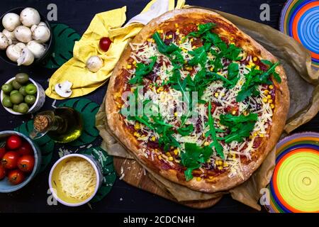 Köstliche hausgemachte Pizza frisch gebackene flache Lay mit bunten Zutaten Und Teller auf dem Tisch Stockfoto