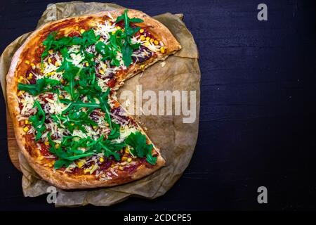 Gekochte Pizza mit einem geschnittenen Teil und leeren Teller dazwischen lustige Konzept. Draufsicht mit Platz für Text Stockfoto