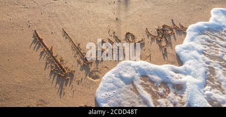 Ich liebe dich - eine Liebesbotschaft auf dem goldenen Sand mit einer Welle, die schäumt und wäscht die Beschriftung Stockfoto