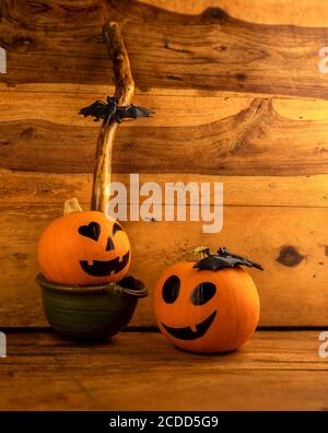 Kleine Kürbisse mit bemalten Gesichtern für Halloween auf Holzhintergrund Stockfoto