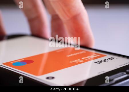 Hand hält iPhone bereit, mit Apple Pay Geldbörse zu bezahlen. Niederländische ING Debitkarte in der Brieftasche Stockfoto