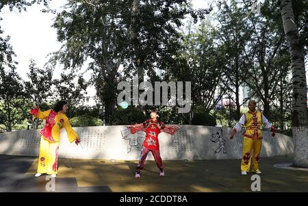 (200828) -- PEKING, 28. August 2020 (Xinhua) -- Mei Yongpei, Dong Yutong und Dong Shulin (L bis R) spielen Diabolo auf dem Wukesong Diabolo Culture Square in Peking, Hauptstadt von China, 11. August 2020. Dong Shulin, 66, lebt mit seiner Frau Mei Yongpei und seiner 9-jährigen Enkelin Dong Yutong in Peking. Dong Shulin begann 2003 Diabolo zu spielen und jetzt spielt die ganze Familie gerne dieses traditionelle Volksspiel, in dem man einen Spinning Top werfen und fangen kann, indem man eine Schnur an zwei Stöcken befestigt. In Dong Shulins Wohnung wurden über 70 Diabolos ringsum platziert. Einige der Diabolos wurden gekauft Stockfoto