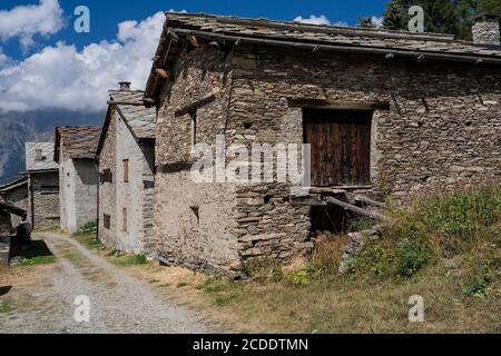 Berghäuser mit Trockenmauern im schönen Dorf Montagne Seu, umgeben von hohen Bergen (Piemont, Italien) Stockfoto