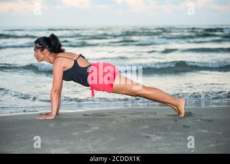 Schönheit Brünette Frau macht einige Fitness-Übungen am Strand Auf See Stockfoto