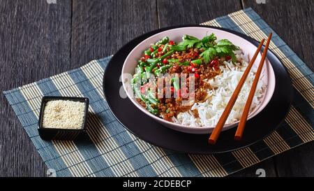 Einfache chinesische grüne Bohnen mit Rührbraten gehacktes Schweinefleisch, Reis bestreut mit Sesam, rote Chili serviert mit Essstäbchen auf einem alten hölzernen Hintergrund, c Stockfoto